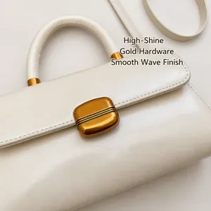 Close-up of golden rectangular metal buckle on white leather vintage handbag
