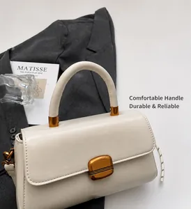 Detail view of cream crossbody bag with golden clasp and round handle on lifestyle background