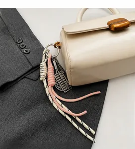 Detail of off-white handbag with decorative pink and silver abacus charm pendant