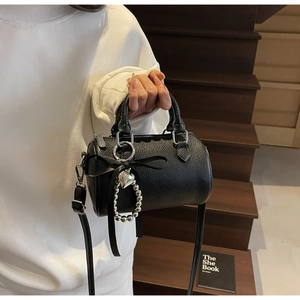 Détail du sac cylindre noir grainé avec bandoulière amovible et nœud en soie élégant