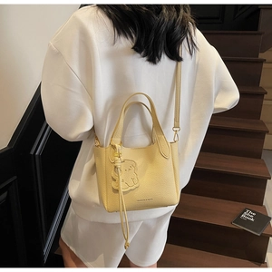 Lifestyle view of a vintage yellow bucket bag with a cute bear charm on a female model