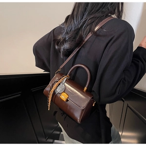Detail showing vintage brown leather bag with gold buckle and tennis racket charm