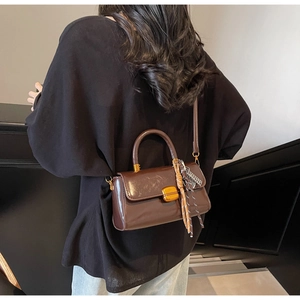 Detail of vintage brown leather handbag with gold buckle and floral scarf handle