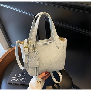 Detail of light blue lychee pattern leather handbag with golden hardware and dog charm