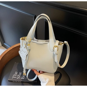Close-up of light blue lychee pattern bucket bag with cute dog charm on a chair