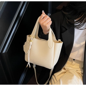 Detail of off-white lychee grain leather bucket bag with gold hardware and logo