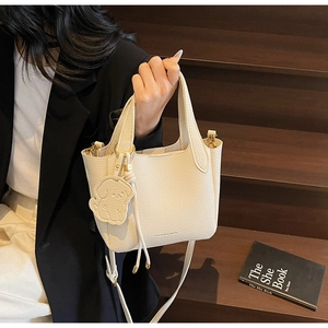Close-up of litchi grain leather bucket bag with a cute puppy pendant and drawstring