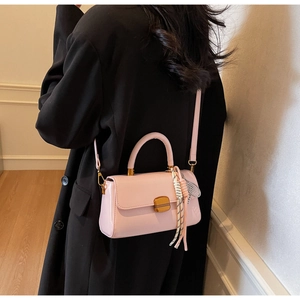 Pink faux leather handbag detail featuring a decorative scarf and tennis racket charm