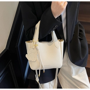 White lychee texture bucket bag with a cute dog charm shown on a fashion model