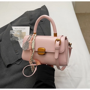 Detail of light pink flap handbag with tennis racket charm and woven rope accessory