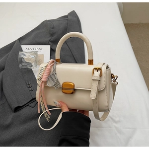 Close-up of cream leather square handbag with gold hardware and tennis racket charm