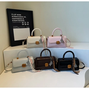 Detail of five mini square bags in various colors with fringe tassels and gold hardware
