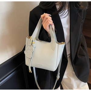 Detail of light blue lychee pattern leather bucket bag with puppy charm and gold hardware