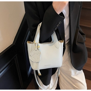 Close-up of light blue lychee leather bucket bag with a cute dog charm and gold hardware