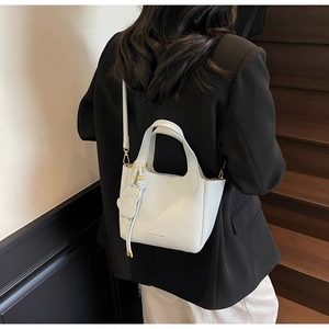 Close-up of premium litchi texture leather bucket bag with dog-shaped charm and gold buckle