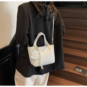 Detail of lychee pattern leather bucket bag with puppy charm and slim shoulder strap