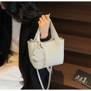 Close-up of light blue lychee pattern bucket bag with cute dog charm and logo details