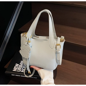 Detail of light blue lychee pattern leather bucket bag with gold hardware and logo