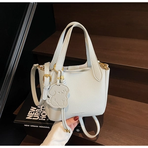 Detail of light blue lychee pattern leather bucket bag with a cute puppy charm