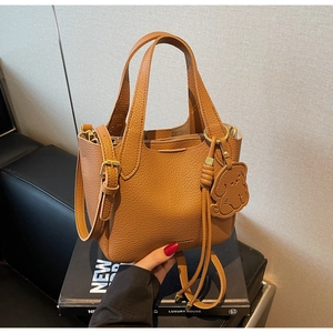 Detail of caramel leather bucket bag with litchi texture and dog-shaped charm