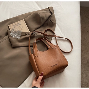 Detailed view of brown litchi grain leather bucket bag with top handles and strap