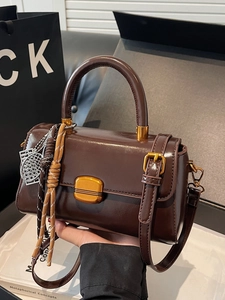 Retro brown glossy leather handbag with gold metal lock and decorative charms on top