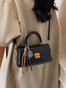 Black glossy crossbody bag with tennis racket charm and rope tassel on model