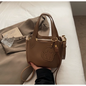 Detail of brown litchi pattern leather bucket bag with cute dog charm and gold hardware