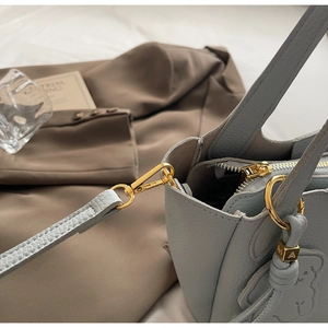 Close-up of pebble leather bucket bag featuring gold hardware and bear charm detail
