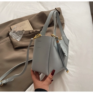 Close-up of light blue lychee pattern bucket bag with golden hardware and hand strap