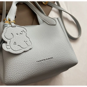 Close-up of light blue lychee pattern leather texture and cute dog pendant detail