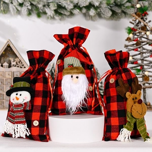 Detail of Christmas buffalo plaid gift bags featuring 3D Santa, snowman and reindeer dolls