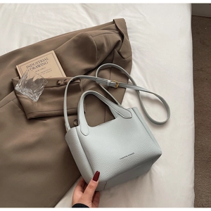 Close-up of light blue bucket bag with lychee grain texture and minimalist gold lettering