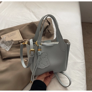 Detail of light blue pebble leather bucket bag with gold hardware and dog charm