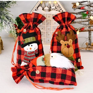 Three Christmas gift bags with red and black plaid fabric and 3D plush holiday characters