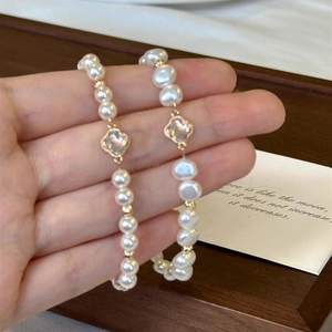 French baroque pearl bracelet with four-leaf clover charms shown on a female hand