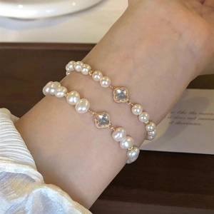Detail of baroque pearl bracelets with golden four-leaf clover charms on wrist