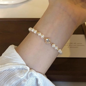 Close-up of elegant baroque pearl bracelet with a golden four-leaf clover charm on wrist