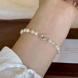 Detailed view of Baroque pearl bracelet with a golden four-leaf clover charm on the wrist