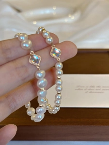 Detail of baroque pearl bracelet featuring iridescent clover charms with gold beaded edges