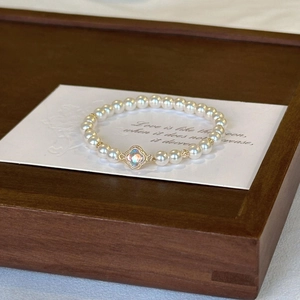 Detailed view of Baroque pearl bracelet with a gold-edged clover pendant on a card