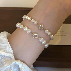Detail of baroque pearl bracelet set with clover charms worn on a woman's wrist