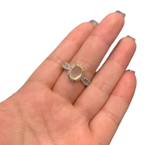 Elegant halo ring featuring an oval white chalcedony stone and two-tone metal band