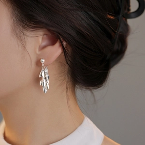 Elegant silver leaf tassel drop earrings worn by a model in a minimalist style
