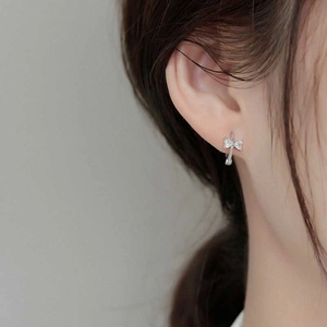 Classic silver bow stud earrings with sparkling zircon stones worn by a female model