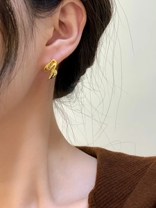Primo piano di orecchini dorati intrecciati su una modella per un look elegante e chic