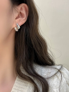 Macro di orecchini a lobo in argento con design a spirale lucido indossati da una modella