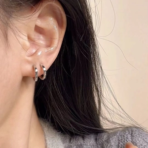 Close-up of minimalist silver hoop earrings on model ear with high polish finish