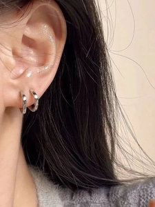 Close-up of minimalist silver hoop earrings on model with high-polish metallic finish