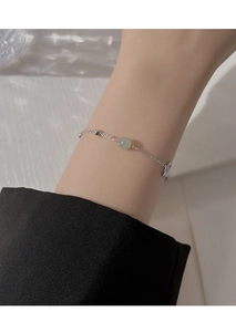 Detail of elegant silver butterfly bracelet with green jade bead worn on wrist